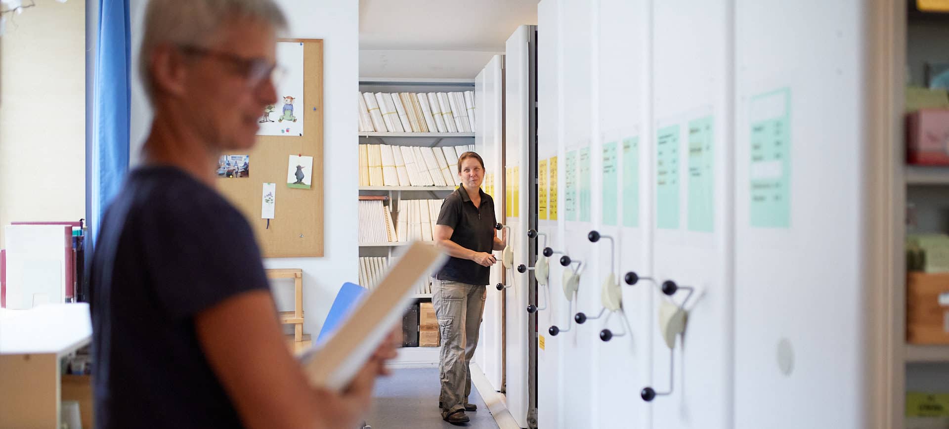 Eine Frau betätigt verschiebbare Regale einer Bibliothek