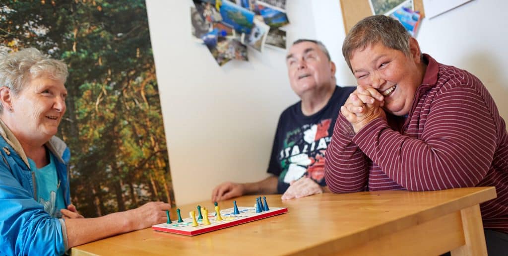 Aktuelles Bild: zwei ältere Damen und ein älterer Herr, alle sehbehindert, spielen Mensch-Ärgere-Dich-Nicht.